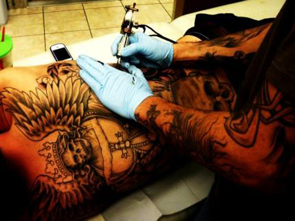 A person with tattoos on their body getting tattooed.